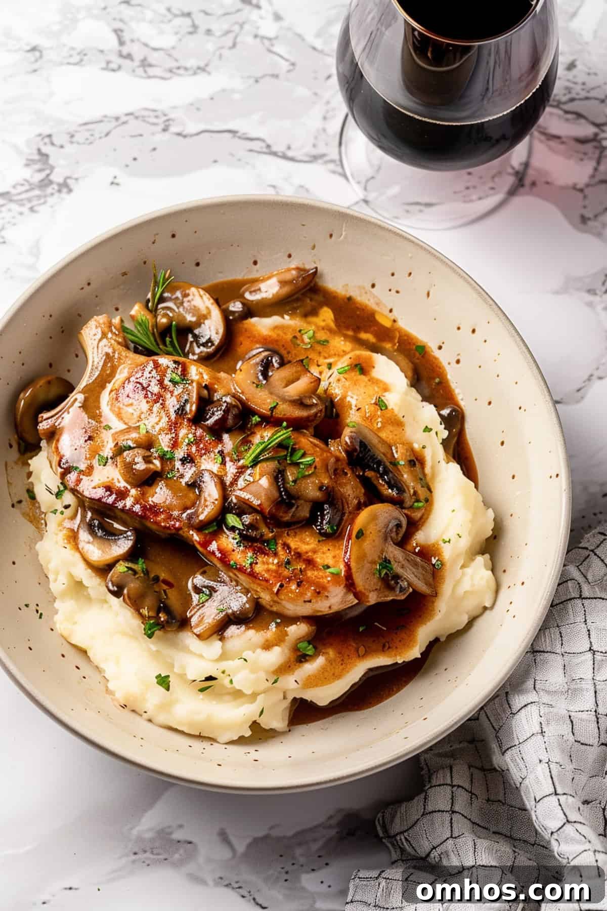 Crock pot pork chops over mashed potatoes with herbs and mushroom sauce.