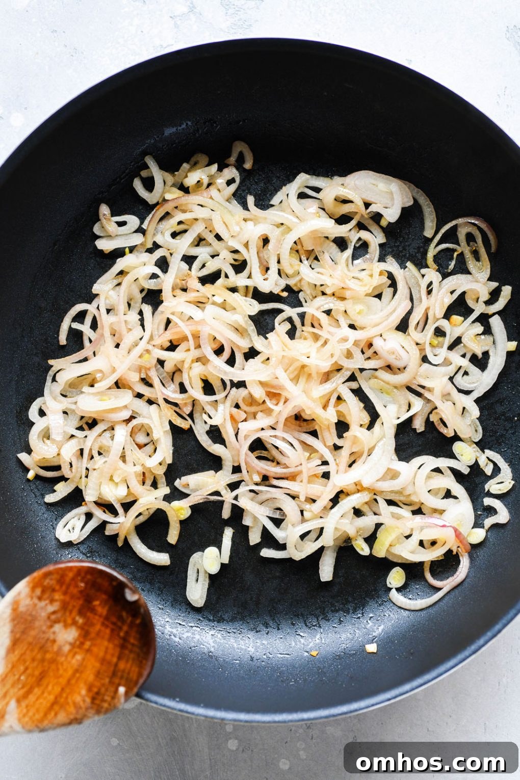 Overhead shot of a medium sized non stick skillet filled with caramelized thinly sliced shallots.