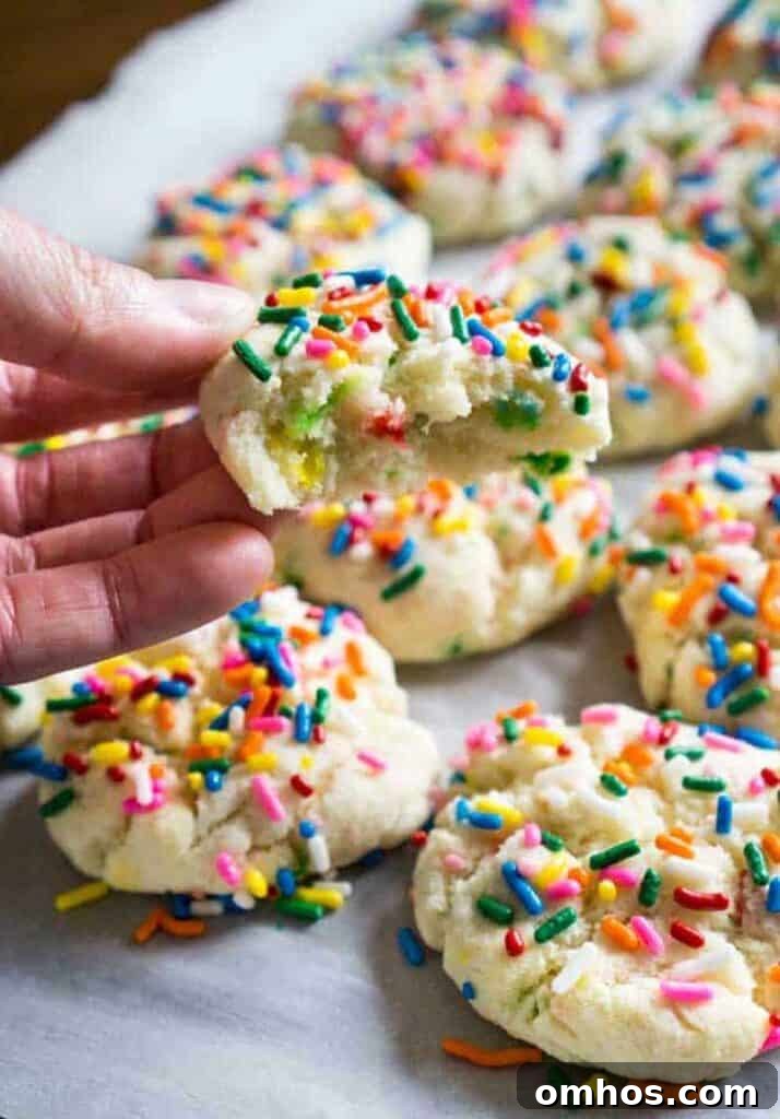 hand holding funfetti cookie with bite taken out with more cookies in background
