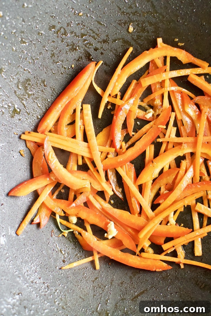 Carrots, Bell Peppers, and ginger cooking in a hot wok.