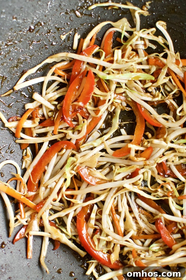 Cabbage, garlic, bean sprouts, and sauce added to the hot wok.