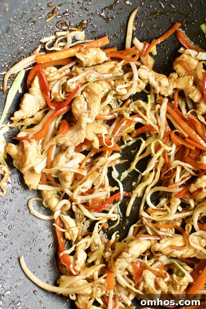 Chicken added back to the cooked vegetable in a super hot wok.