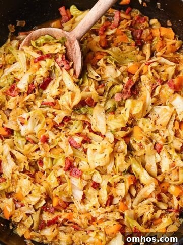 Southern fried cabbage with bacon in a skillet with serving spoon.