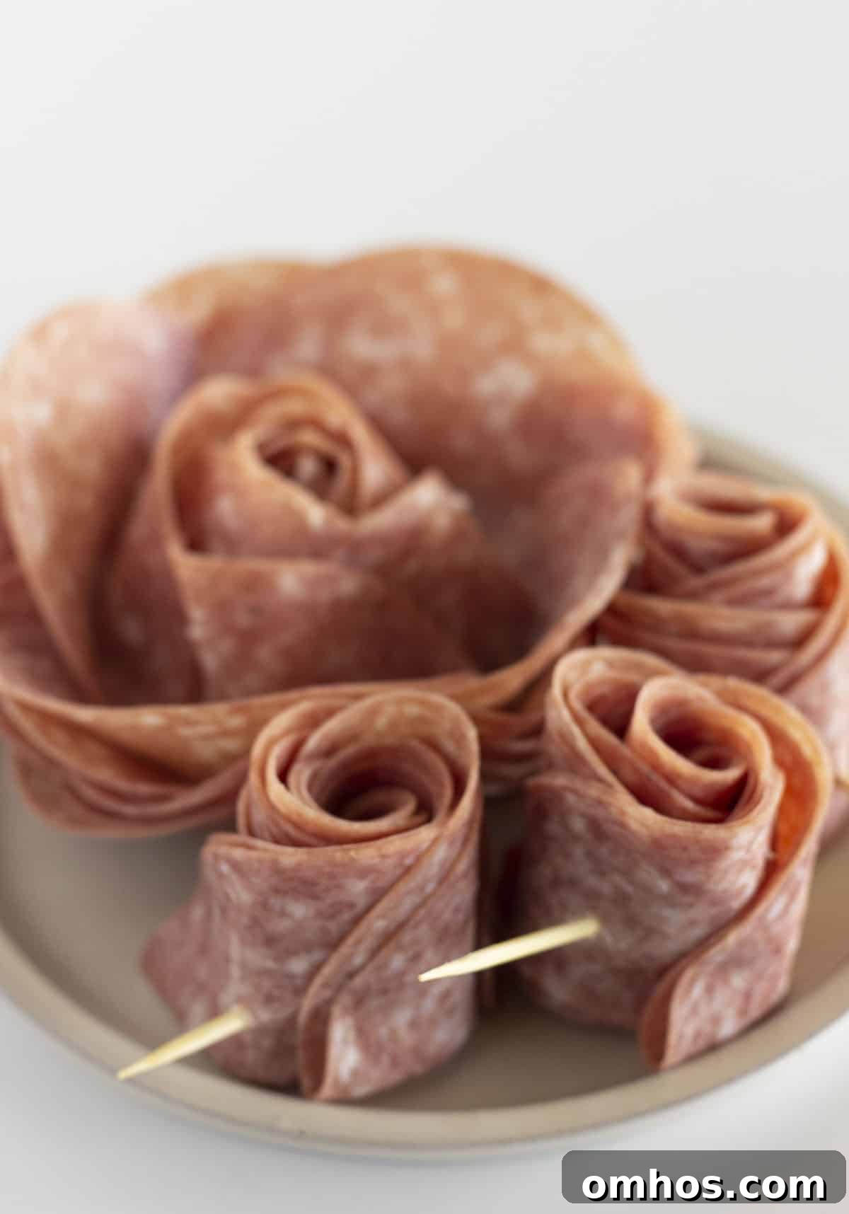 Salami roses on a white plate.