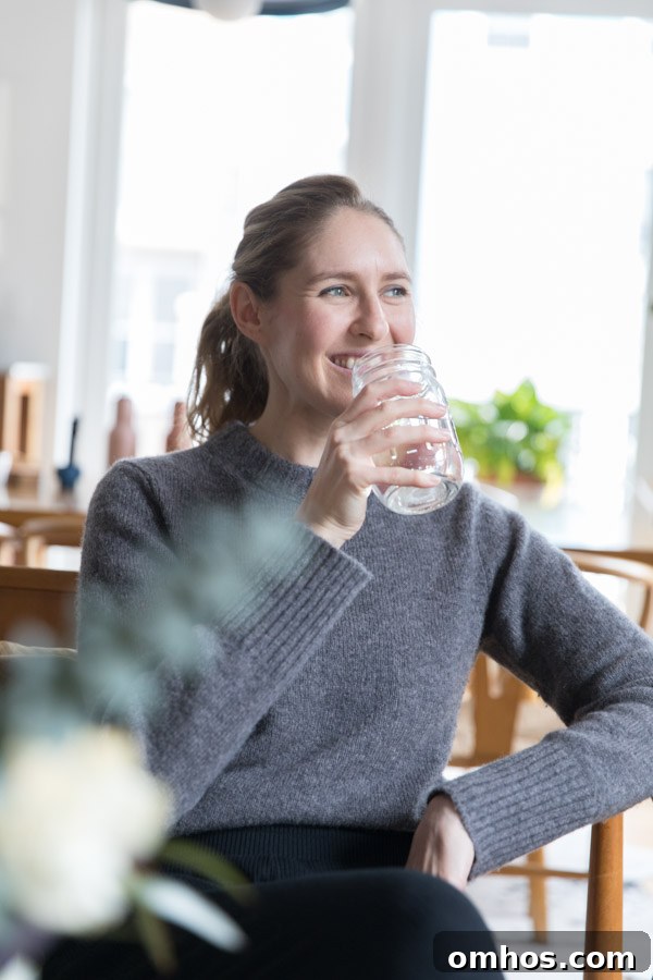 Natural Perioral Dermatitis Remedies Dermatologists Don't Share 6 Phoebe Lapine the author taking a sip of a glass of water while sitting in a chair