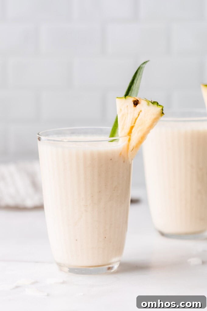 two glasses of pina colada smoothie on a marble contertop
