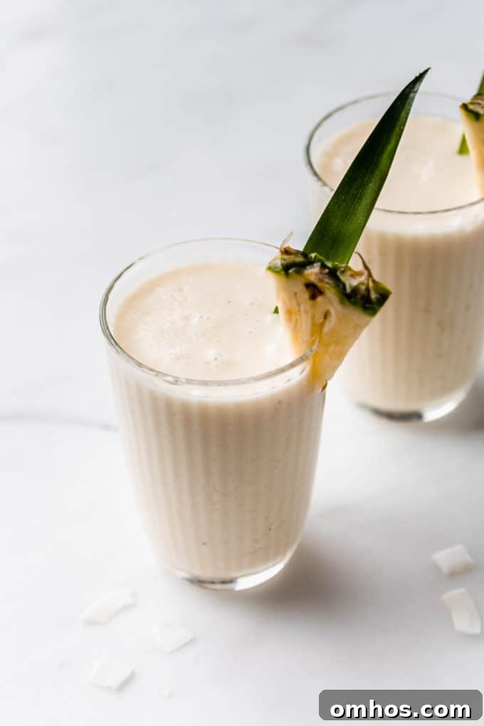 a pina colada smoothie in a glass with a slice of pineapple