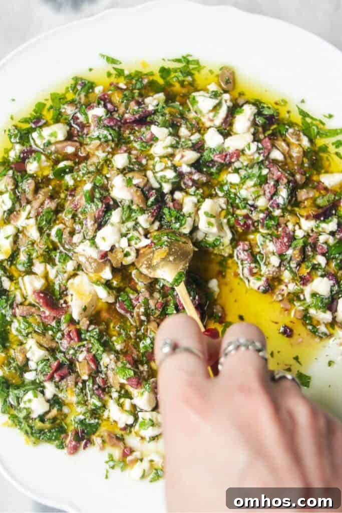Hand mixing ingredients for Greek dipping oil in a large white plate.