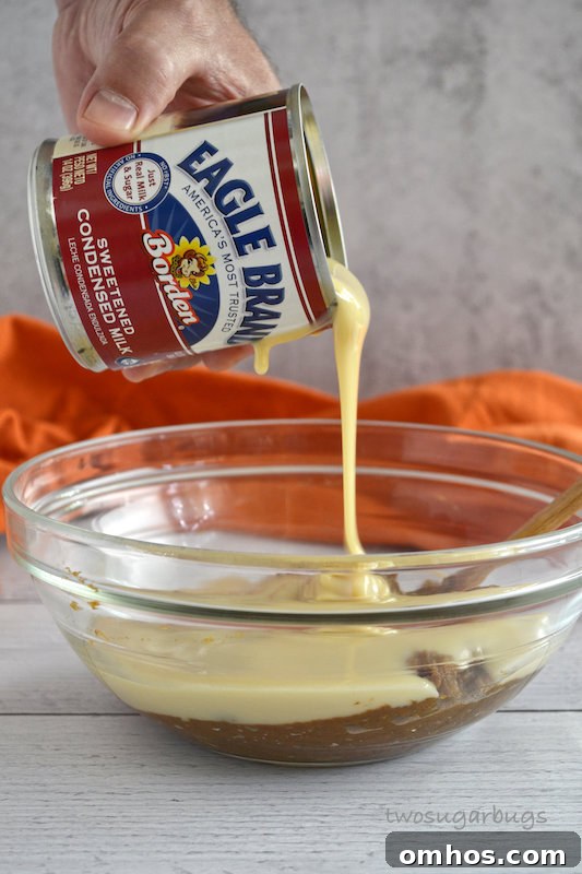 hand pouring Eagle Brand Sweetened Condensed milk into bowl