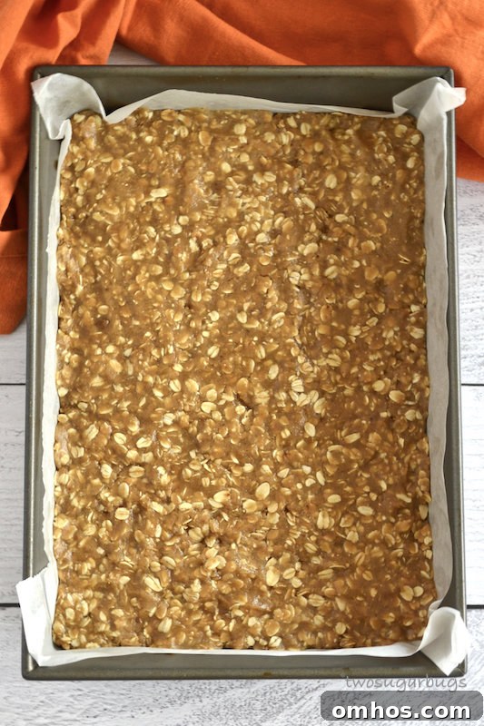 unbaked oatmeal spice layer in parchment lined baking sheet