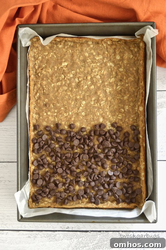 Baked oatmeal spice layer with chocolate chips over half.