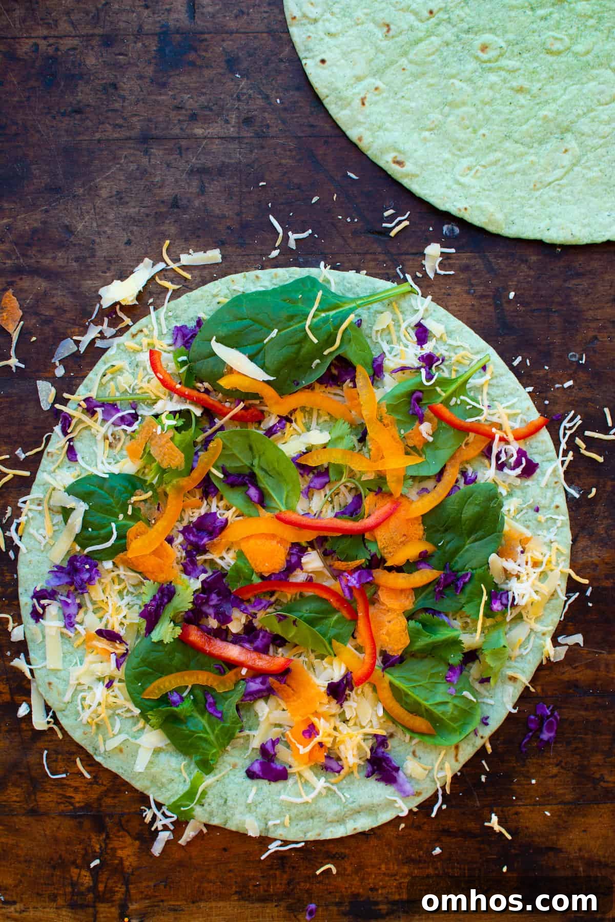 How to Make a Rainbow Vegetable Quesadilla 5 Overhead image of a veggie quesadilla with shredded cheese on a spinach flour tortilla sitting on a wood table.
