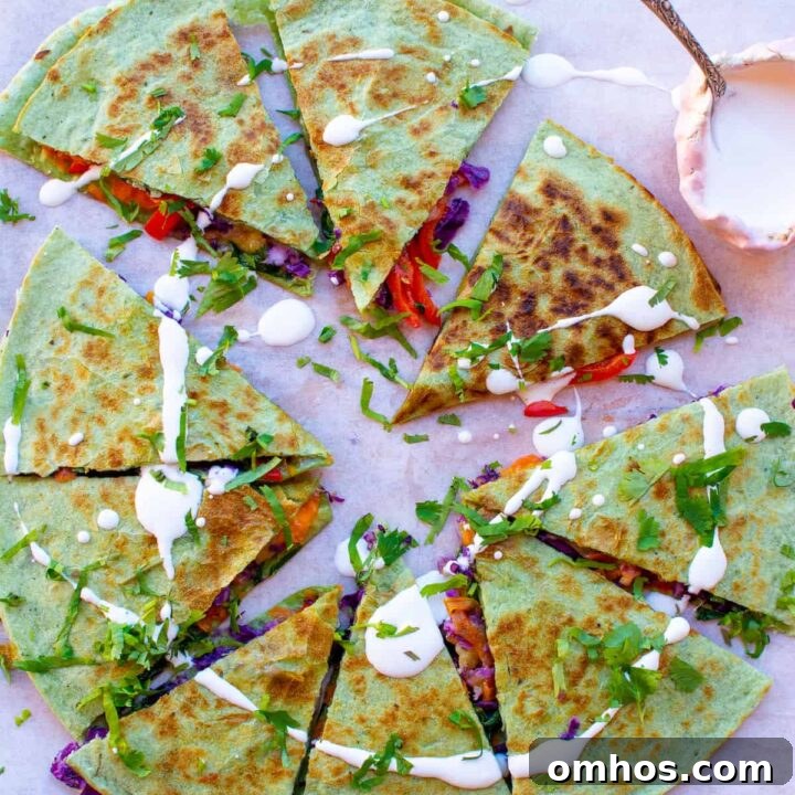 Overhead image of a veggie quesadilla on a cutting board with a pink little bowl of sour cream on the side.
