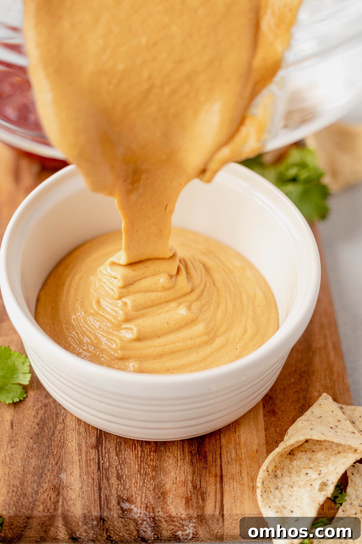 pouring cashew queso into a sauce cup