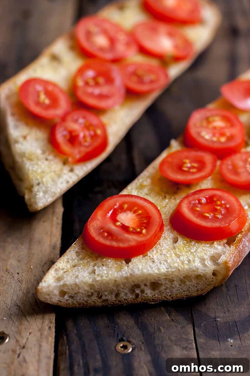 Spaghetti Squash Marinara with Chili Oil Tomato Garlic Bread 6 Vertical image of bread slices topped with fresh tomatoes on a wooden surface.