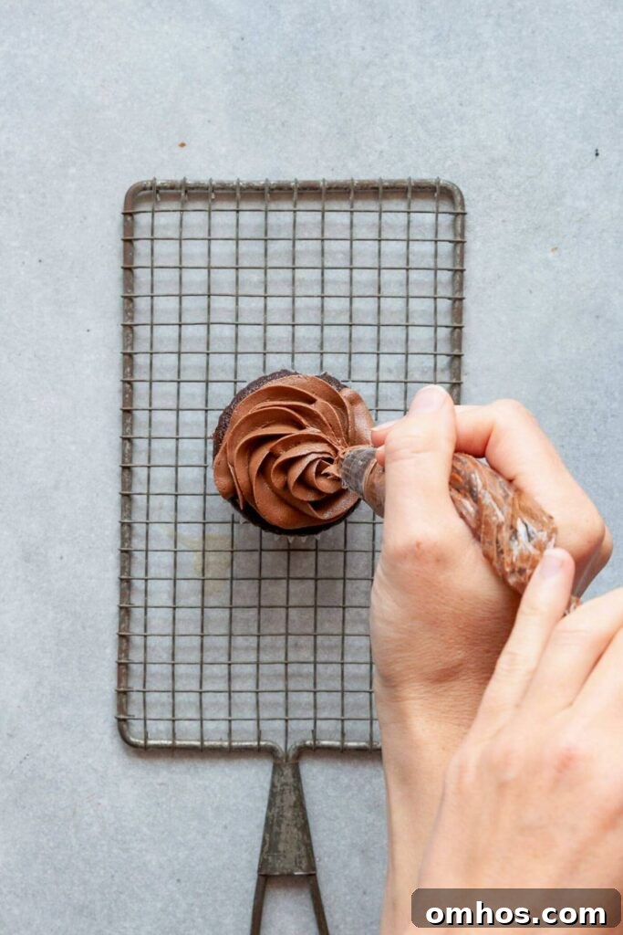piping vegan chocolate buttercream on to a cupcake