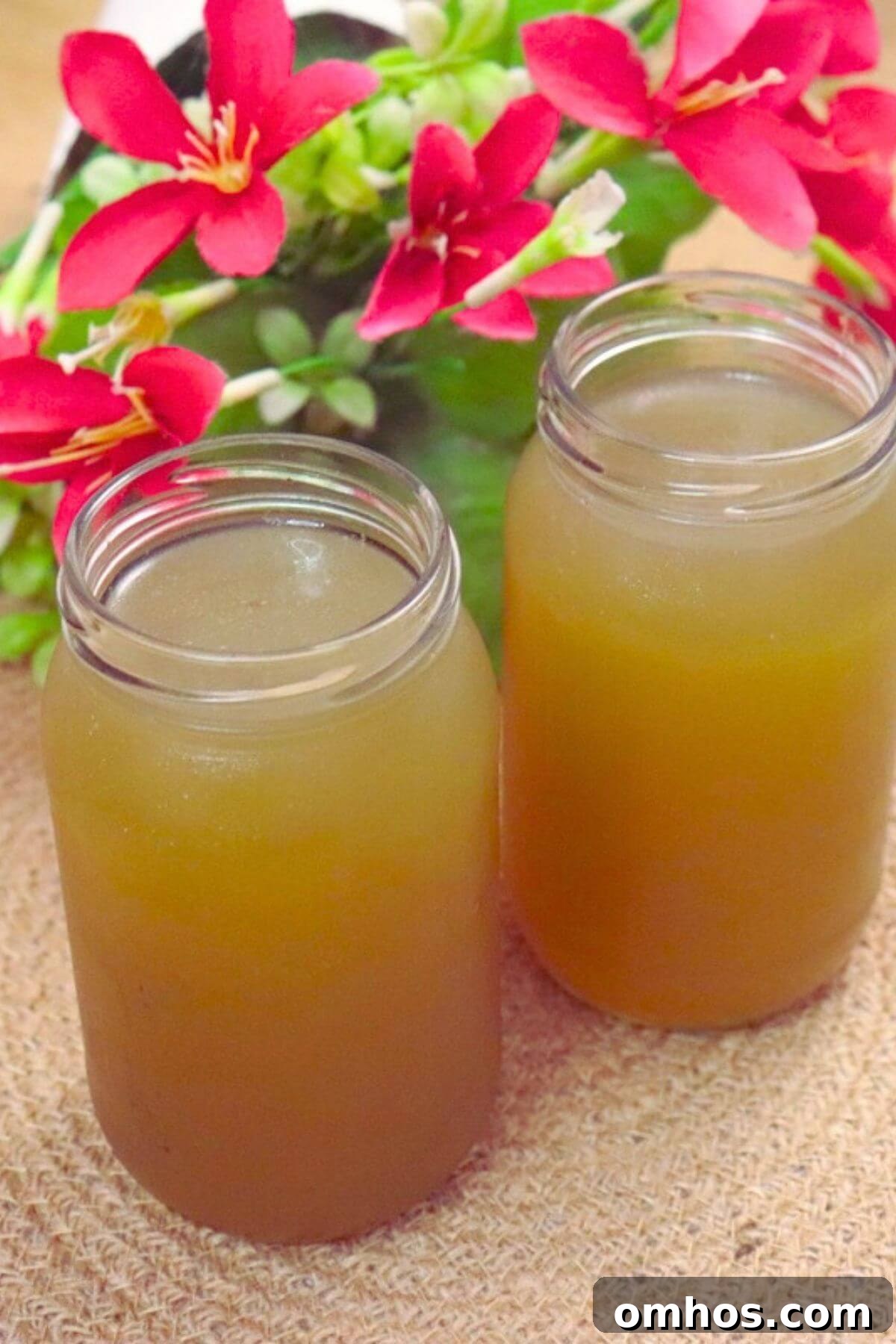 Homemade chicken stock stored in two glass bottles, placed side by side.