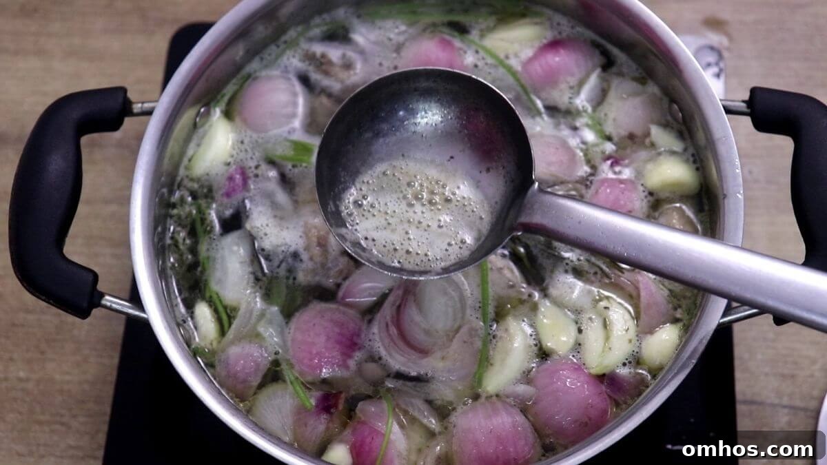 Foam being skimmed from simmering chicken stock.