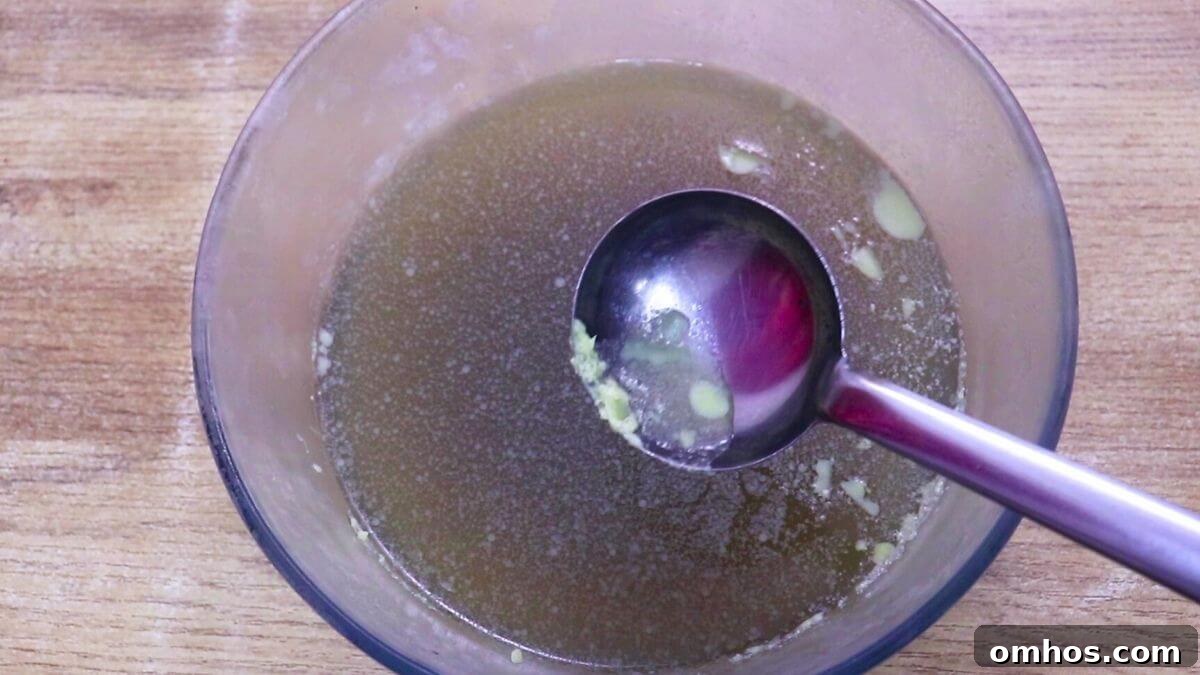 Fat layer being removed from cold homemade chicken stock.