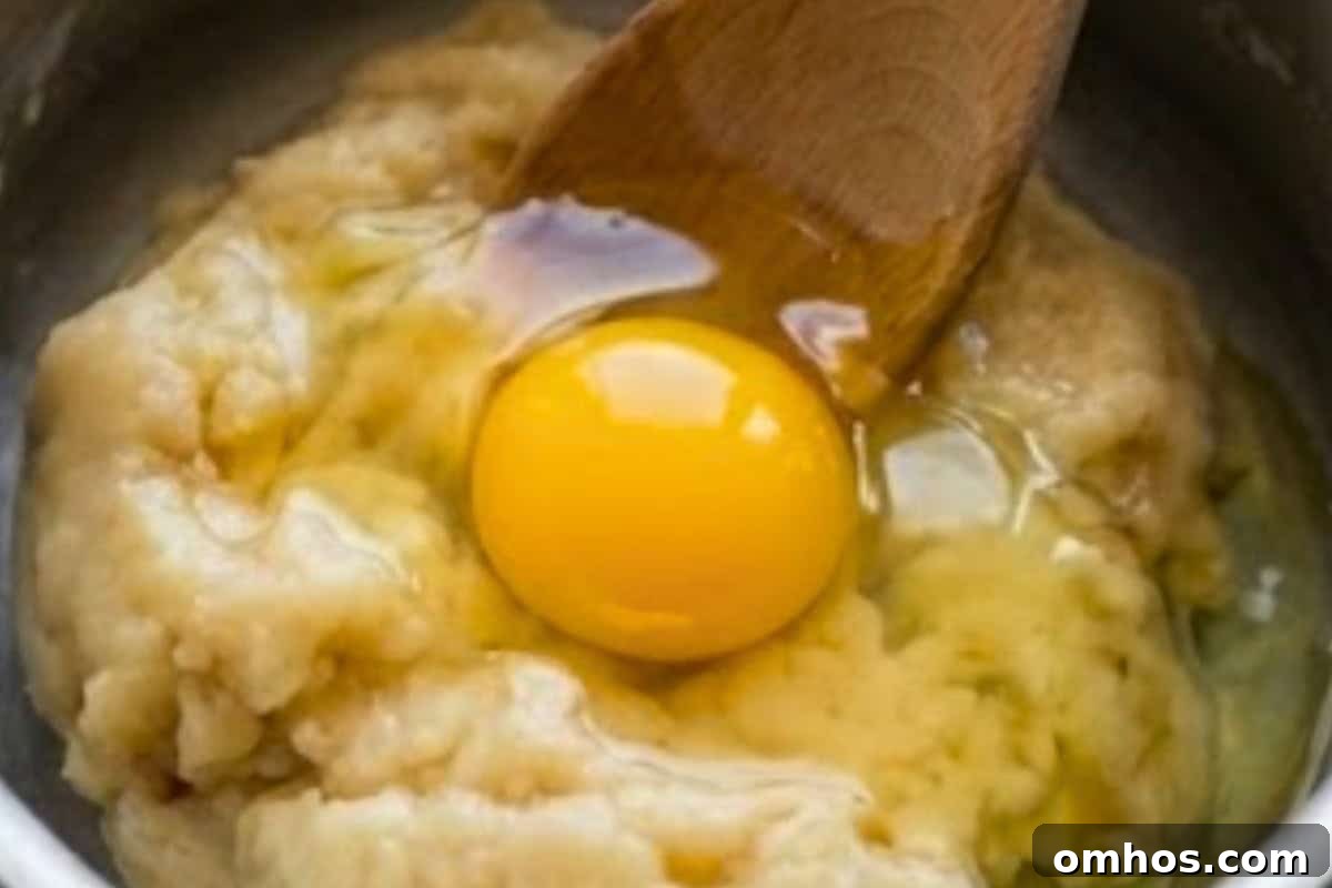 Remove the dough from heat and let it cool for about 5 minutes until warm to the touch. Beat in one egg at a time