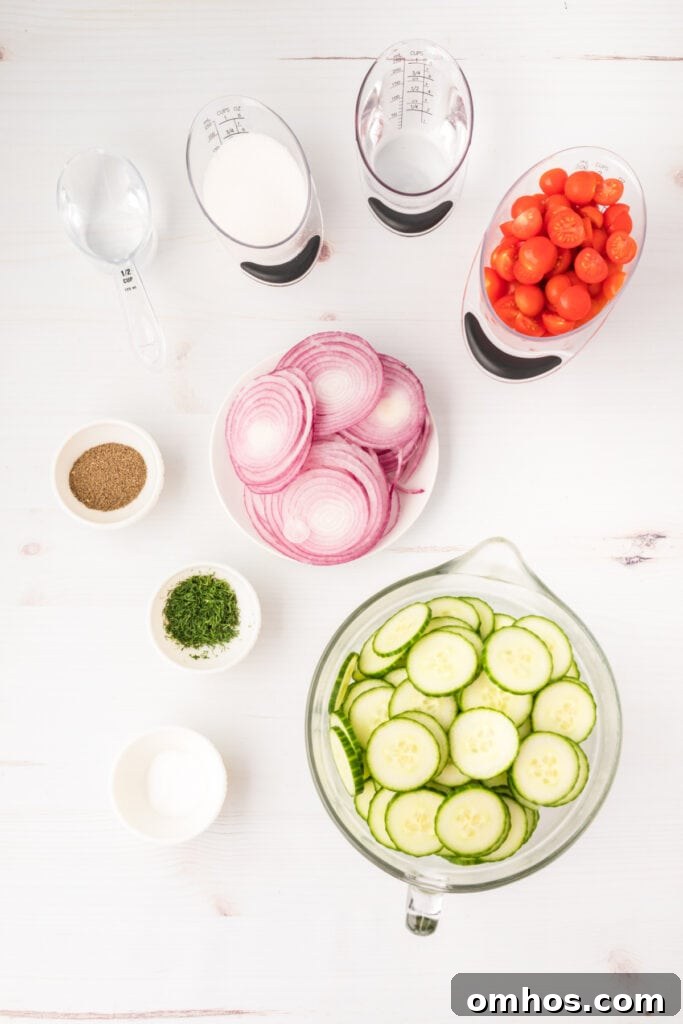 Overhead shot of salad ingredients in bowls, including cucumbers, tomatoes, red onions, dill, and vinegar