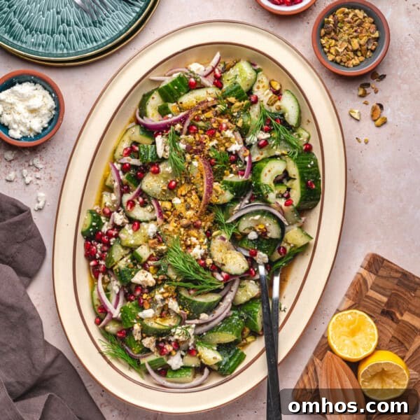 Overhead square image of smashed cucumber salad in a large platter, surrounded by ingredients and serving tools