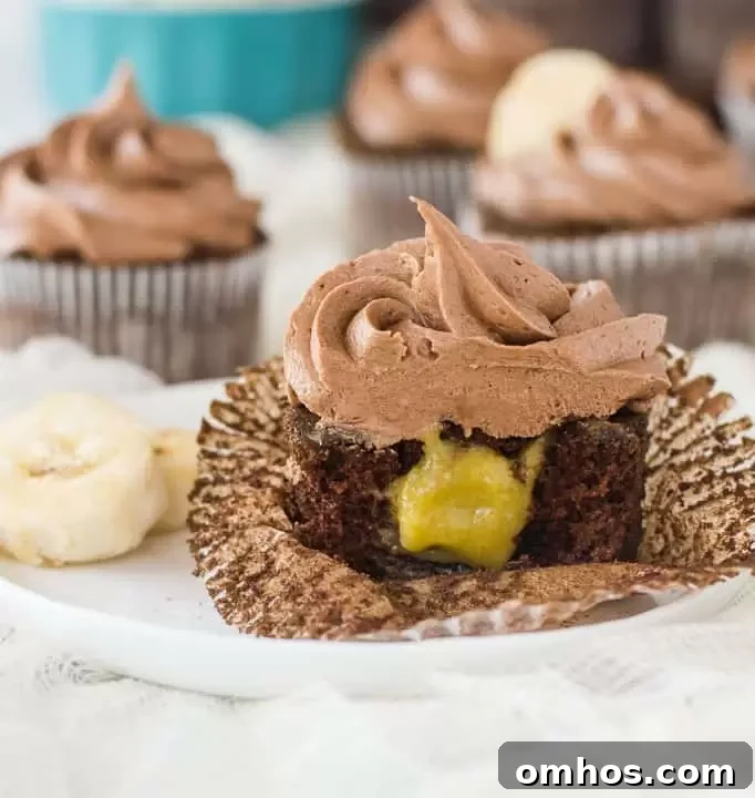 Moist Chocolate Banana Cupcakes Recipe 6 cupcake on a plate sliced in half to show the filling with more chocolate banana cupcakes in the background