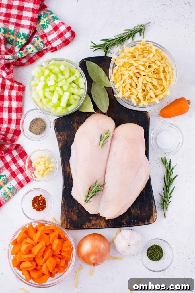 Crockpot chicken noodle soup ingredients in bowls on a white surface, with chicken breasts on a cutting board.