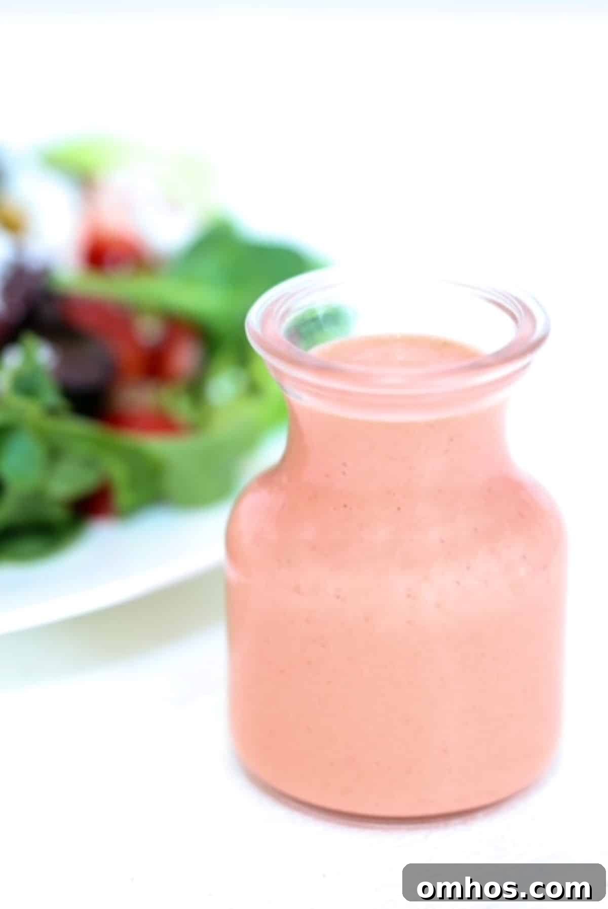 Homemade Strawberry Balsamic Vinaigrette Recipe 2 Strawberry Balsamic Salad Dressing in a glass dressing jar with a salad in the background.