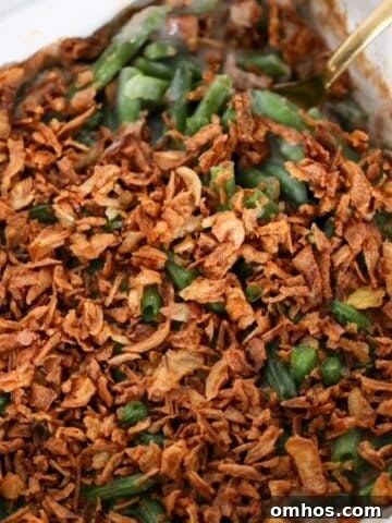 Green Bean Casserole in a white, square baking dish with a serving spoon.