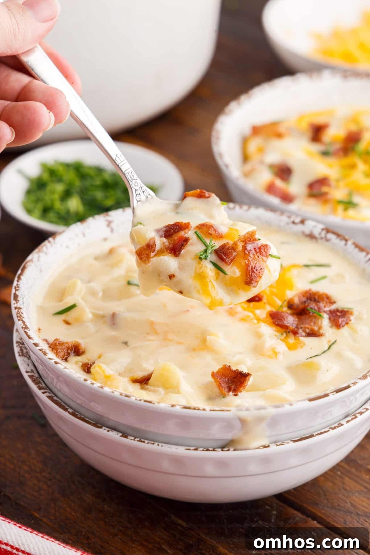 bacon cheddar potato soup in bowls with a spoon lifting soup out