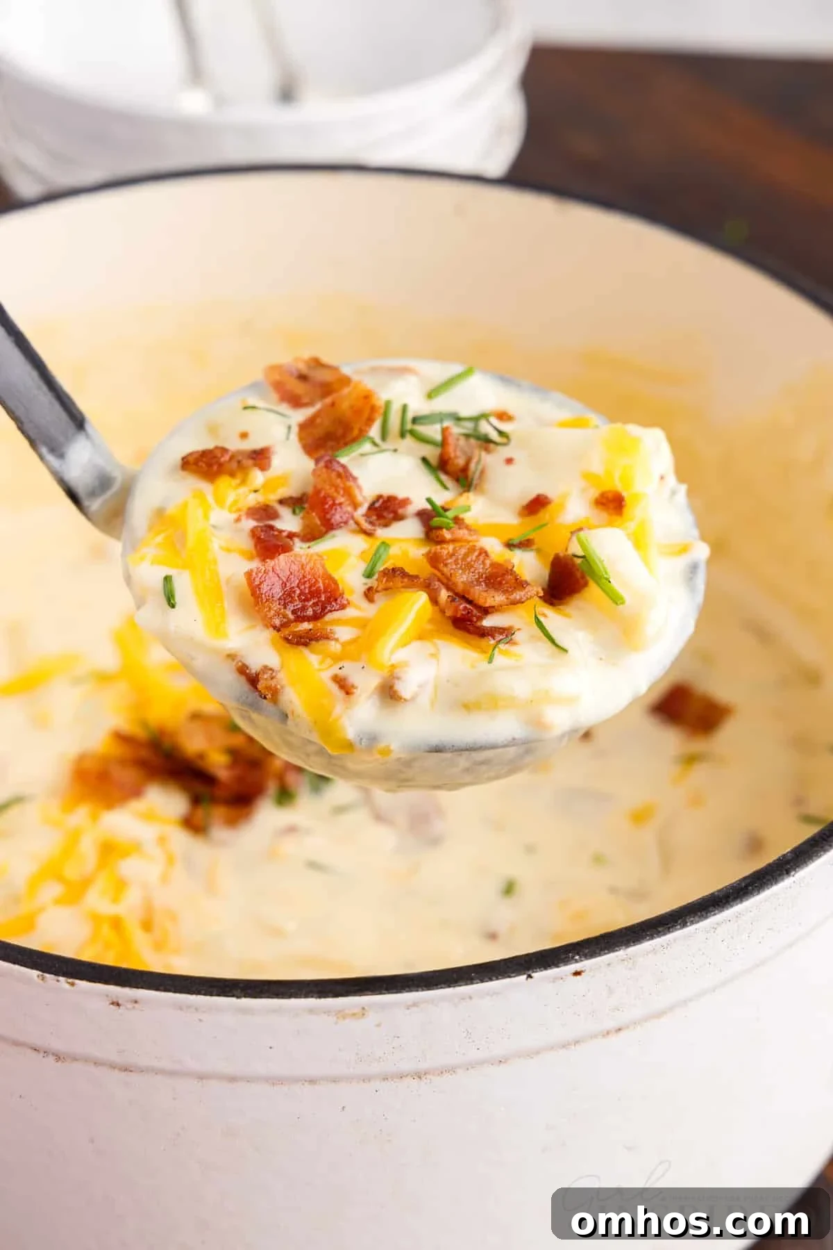 front view of a ladle full of bacon cheddar potato soup