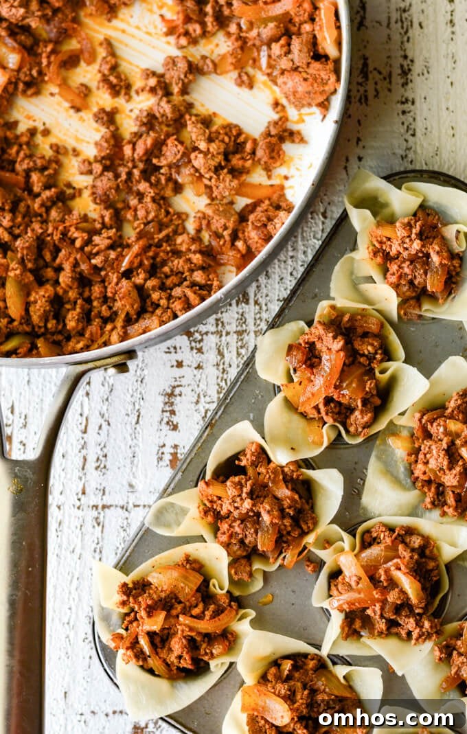 Wontons filled with chorizo sit in a mini muffin tin. A skillet with the meat sits next to the tin.