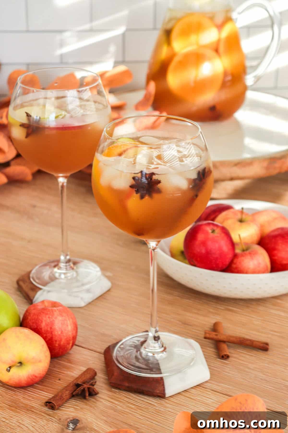 Apple cider sangria in a wine goblet with apples on the table.