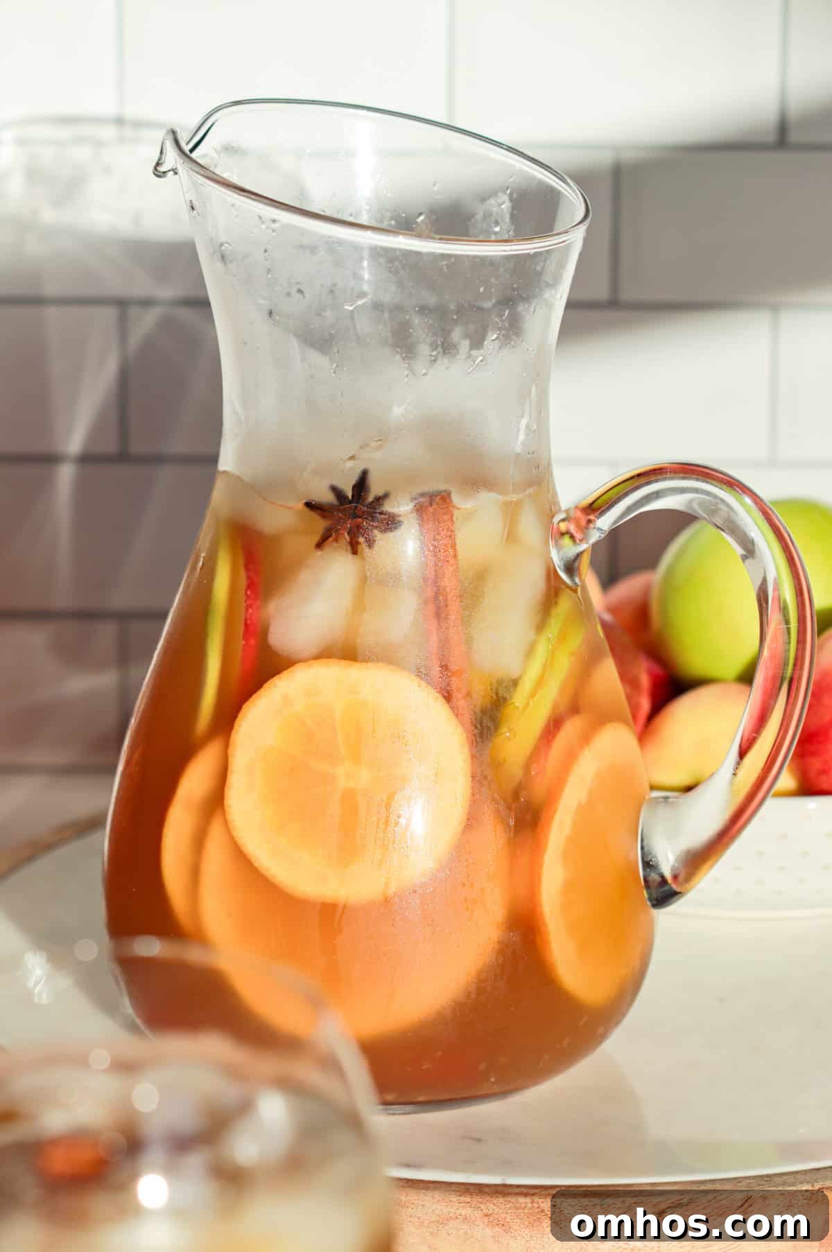 Pitcher of white wine sangria with apples and cinnamon in a pitcher.