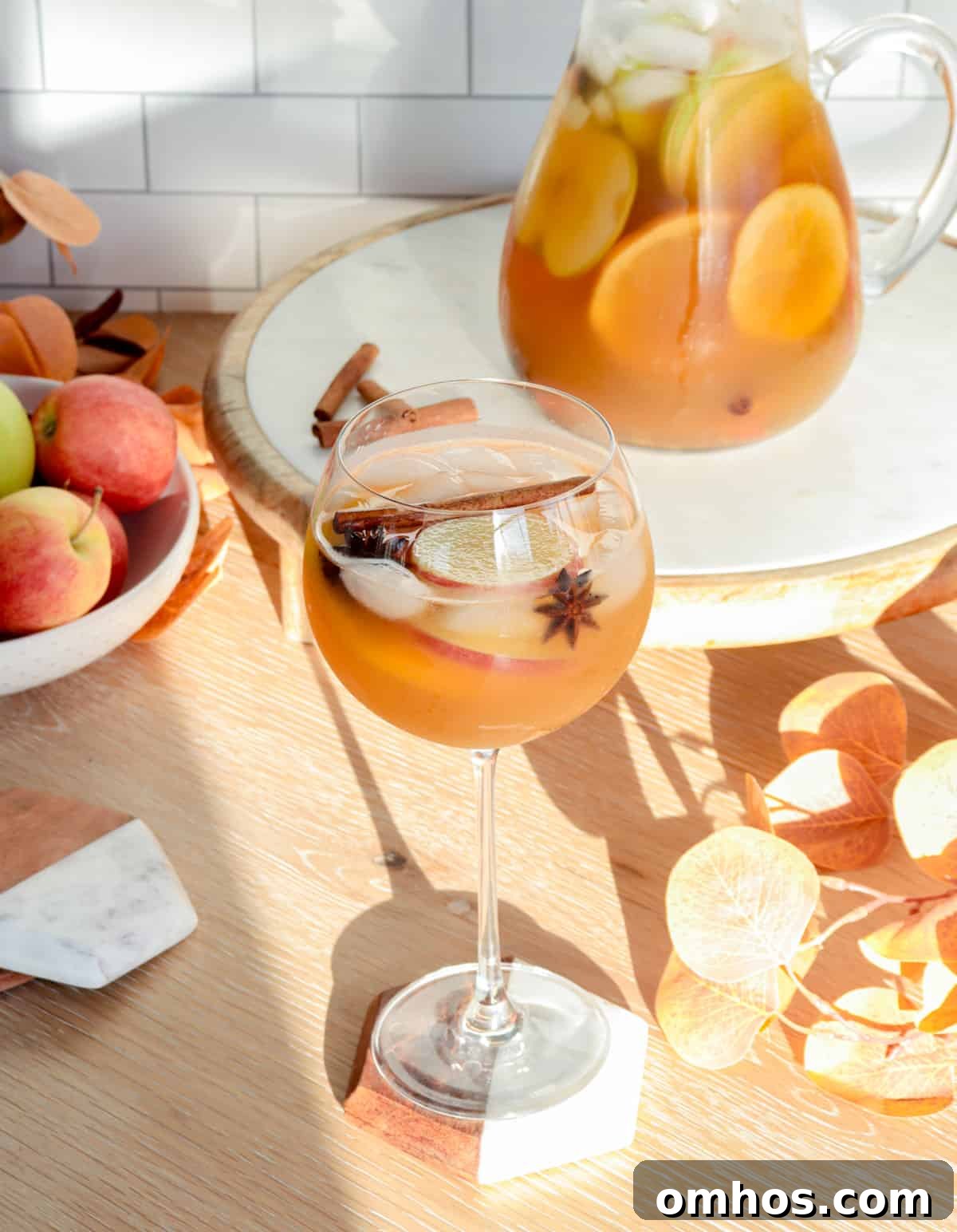 Apple crisp fall sangria in a large wine glass with apples.