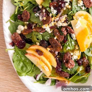 Fall apple pecan salad on a white plate with gorgonzola cheese.