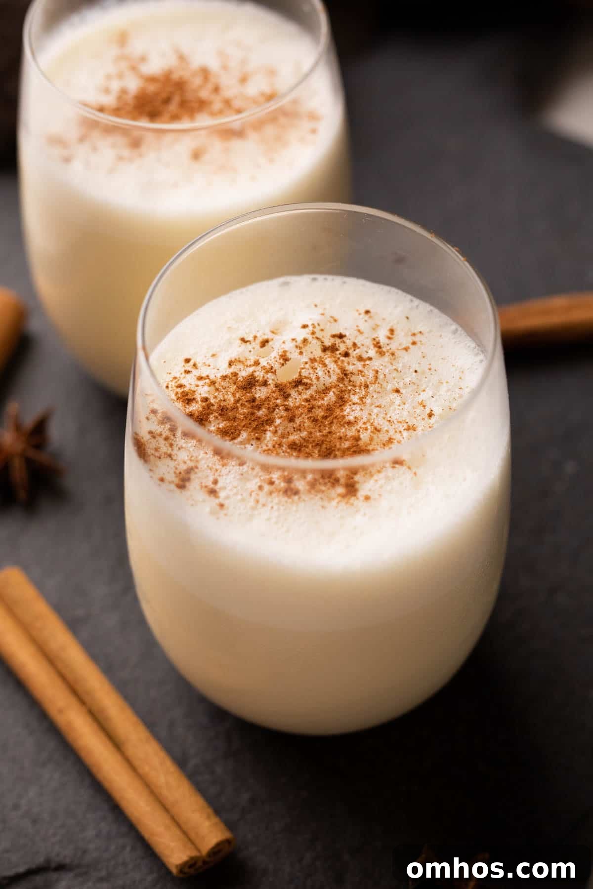 Picture of two glasses of non alcoholic eggnog with powdered cinnamon sprinkled on it