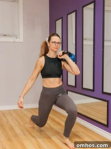 How to Make Home Workouts More Intense Without Weights 6 Woman in sports bra and tights performing a kettlebell lunge.
