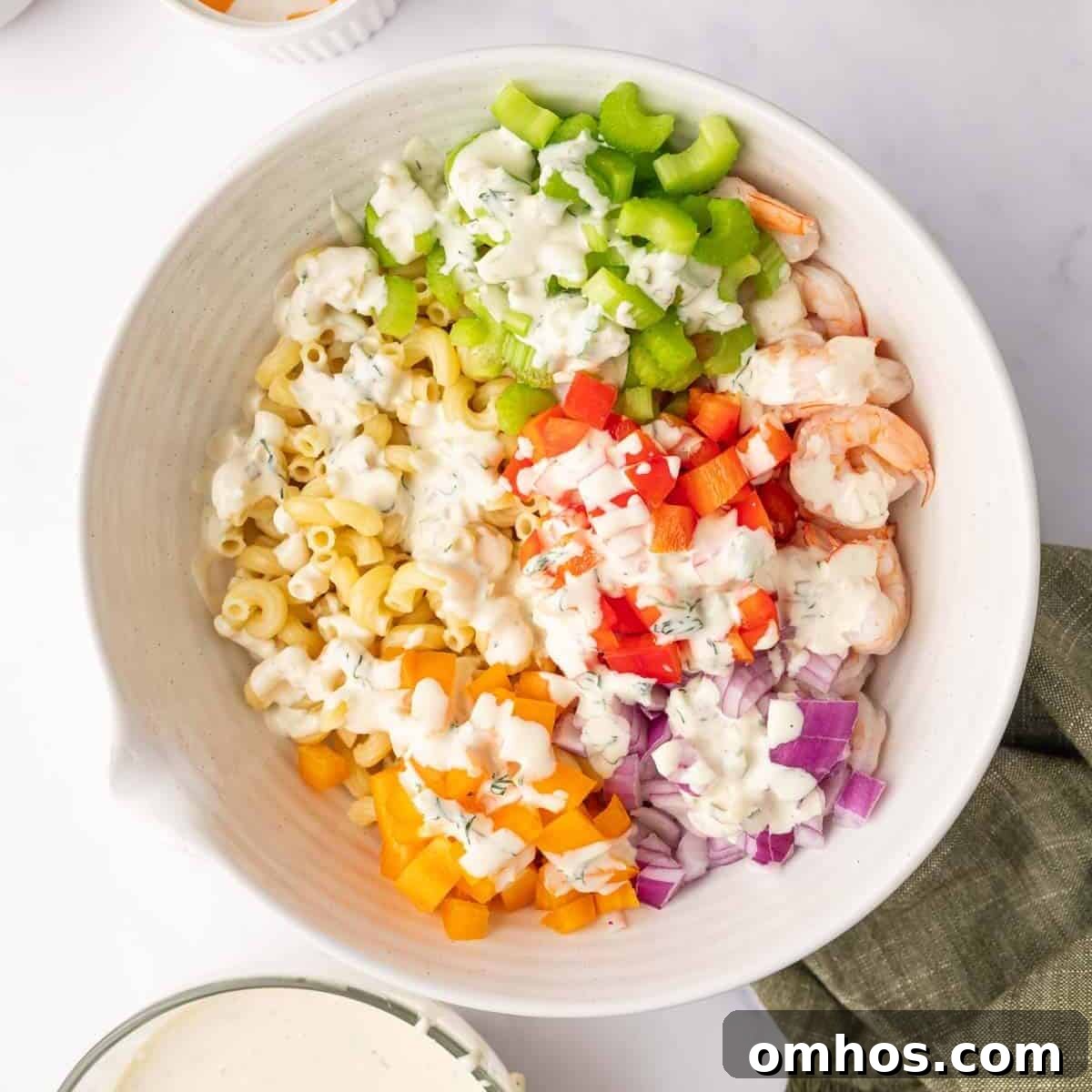Salad ingredients are layered in a bowl and topped with dressing.