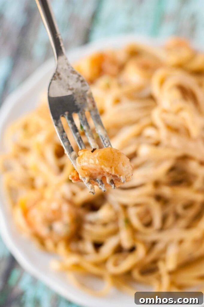 Cajun Shrimp Pasta on a white plate with a fork full of shrimp