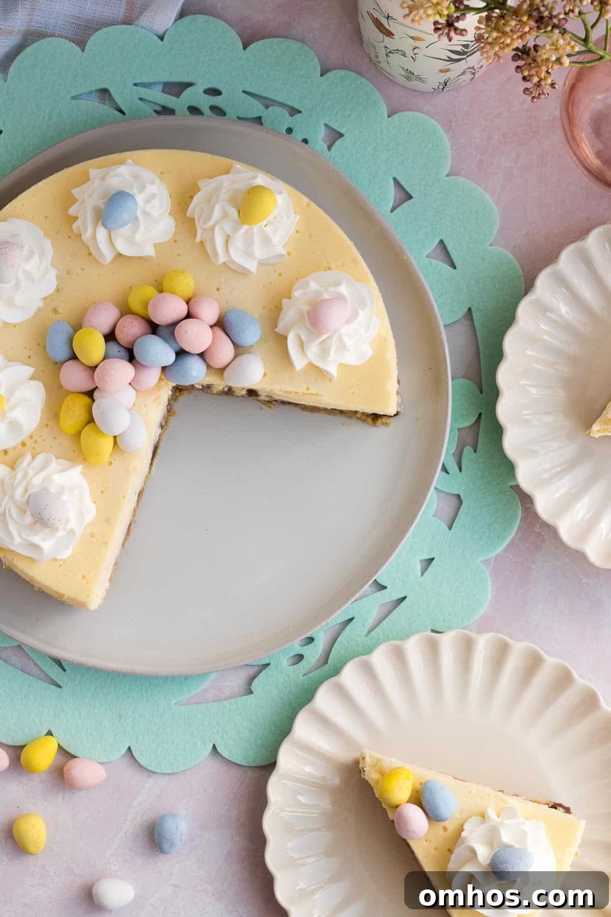 No-Bake Easter Egg Cheesecake Recipe 4 top view of an Easter egg cheesecake with 2 slices cut out and on scalloped plates to the side