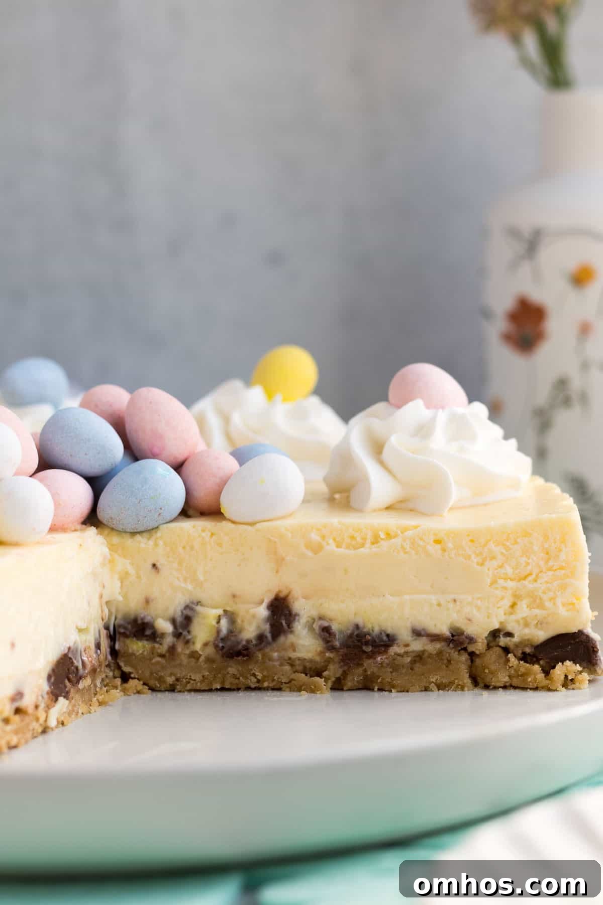 No-Bake Easter Egg Cheesecake Recipe 6 close up of an Easter egg cheesecake on a gray plate with a piece cut out showing the inside of the cheesecake