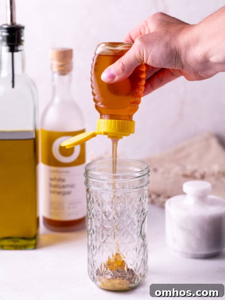 hand squeezing honey into a mason jar