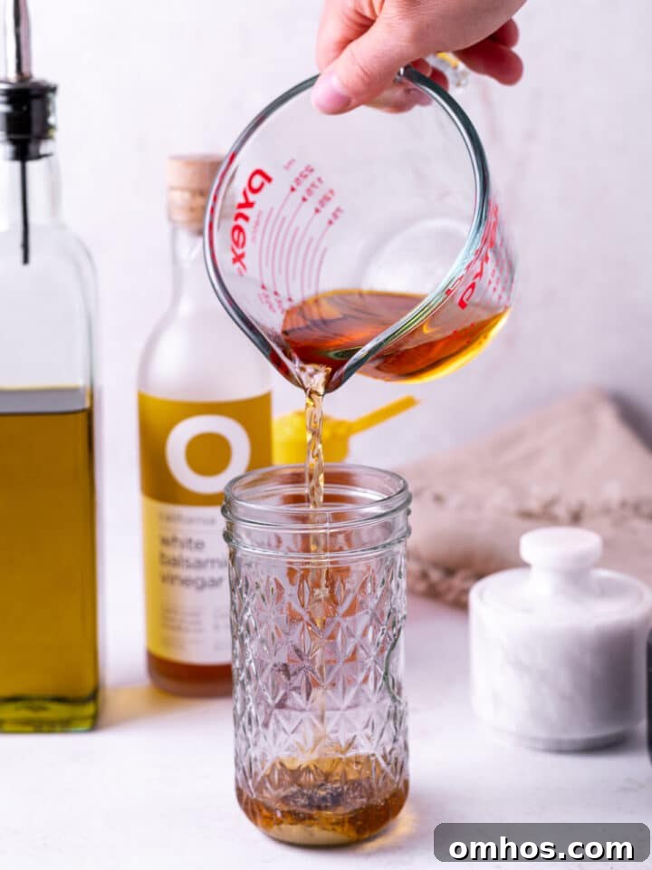 hand pouring vinegar from a liquid measuring cup into a jar