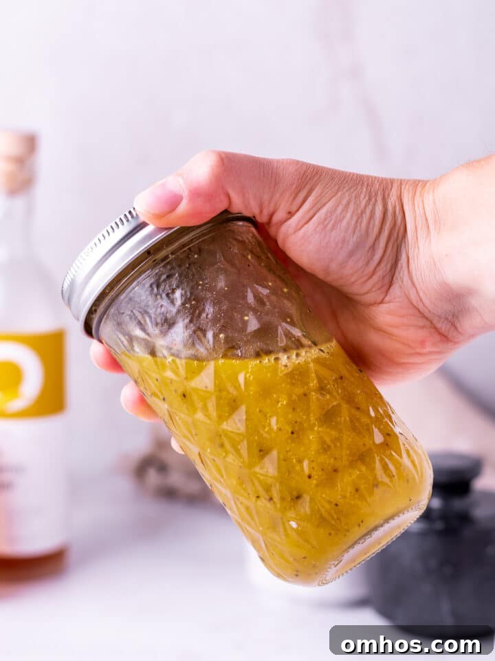 hand shaking a jar of white balsamic vinaigrette