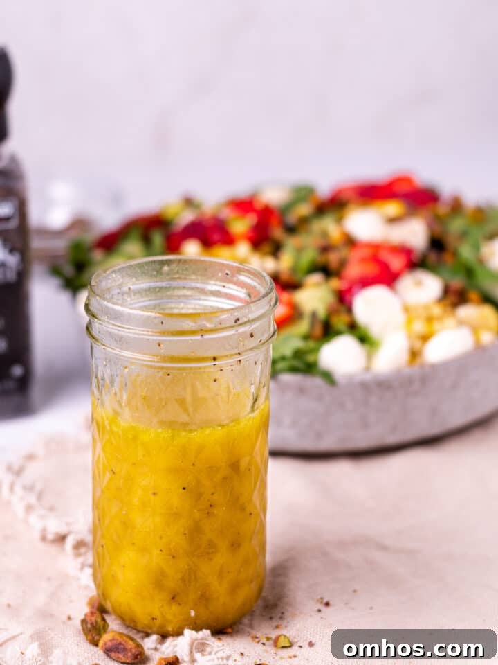 jar of white balsamic vinaigrette with a large summer salad