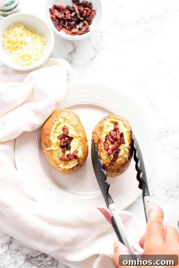 Baked potatoes topped with cheese and bacon and served on a white plate.