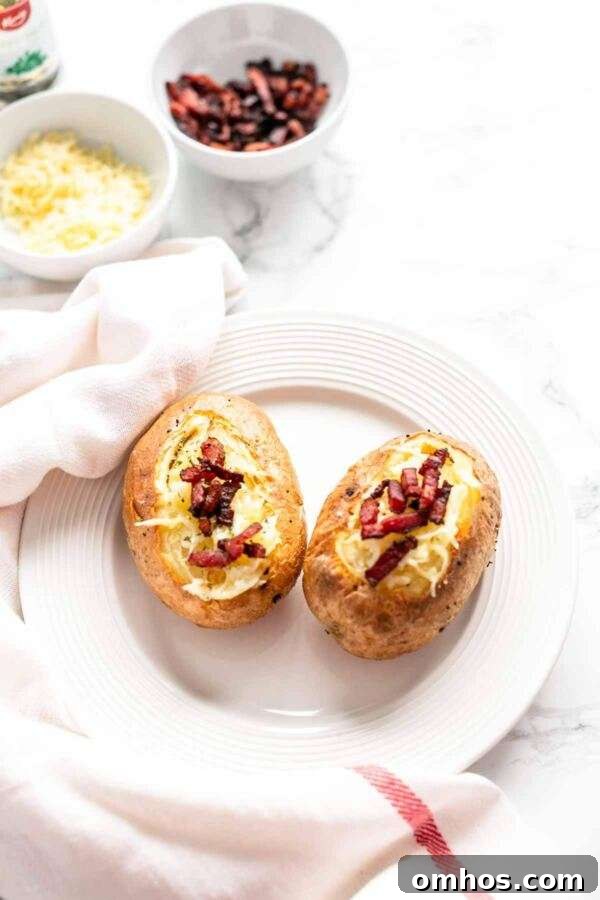 Close up of baked potatoes with a topping of shredded cheese and crispy bacon.