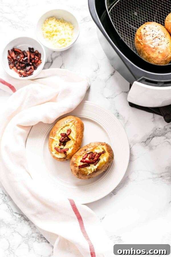 Potatoes baked in an Air Fryer presented on a white plate and topped with shredded cheese and grilled bacon.